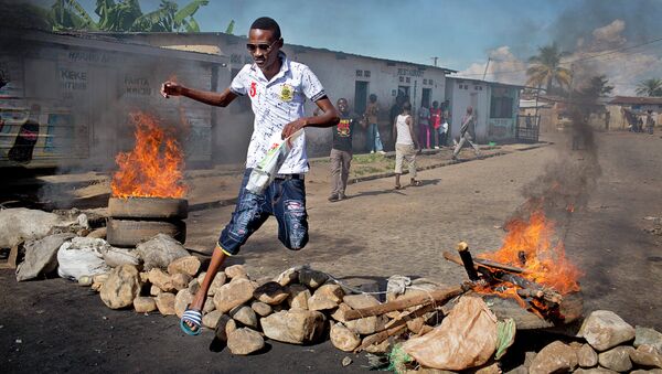 A civilian jumps over a burning barricade of rocks erected by residents to protect themselves from police, in a northern district of the capital Bujumbura, in Burundi Thursday, May 14, 2015 - Sputnik International