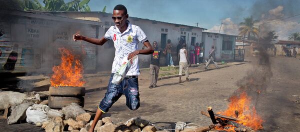 A civilian jumps over a burning barricade of rocks erected by residents to protect themselves from police, in a northern district of the capital Bujumbura, in Burundi Thursday, May 14, 2015 - Sputnik International