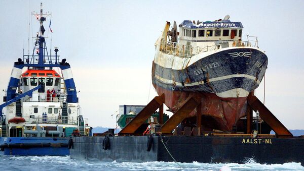 A picture taken on July 13, 2004 shows the wreckage of French trawler Bugaled Breizh, installed at a barge, as it is being towed, and escorted by military ships, towards a French military port of Brest. file photo - Sputnik International