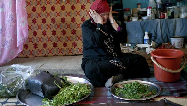 Syrian refugee Ruwaida al-Ahmad, 45, weeps while preparing to cook grass as she tells her story to the Associated Press inside her room that used to be a classroom at the Al-Rama Public School that has become home to 22 Syrian families at the Lebanese-Syrian border village of Al-Rama, north Lebanon - Sputnik International