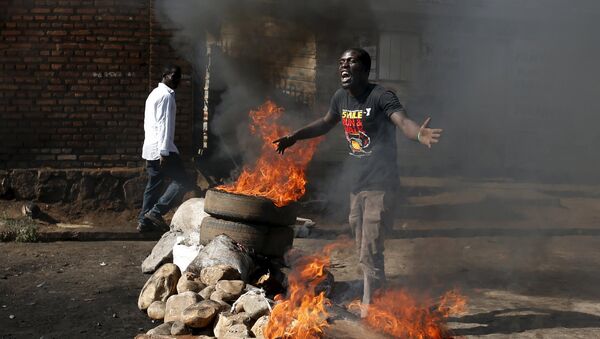 A protester, who is against President Pierre Nkurunziza's decision to run for a third term, gestures in front of a burning barricade in Bujumbura, Burundi May 14, 2015 - Sputnik International