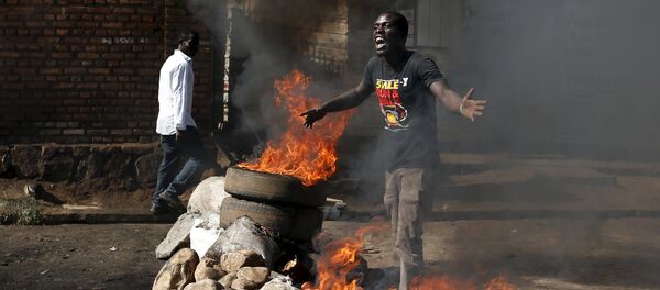 A protester, who is against President Pierre Nkurunziza's decision to run for a third term, gestures in front of a burning barricade in Bujumbura, Burundi May 14, 2015 - Sputnik International