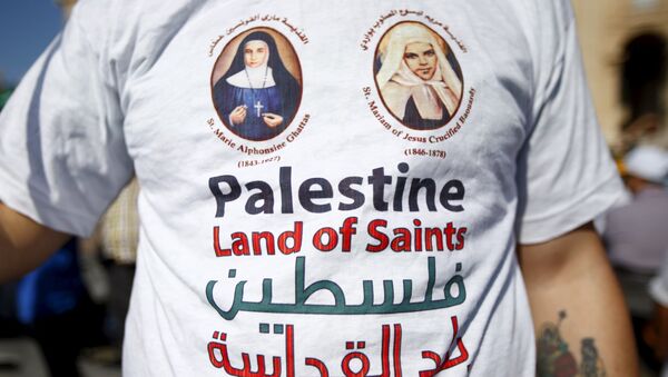 A member of the faithful wears a t-shirt with the pictures of the two Palestinian nuns being canonised before Pope Francis leads a ceremony for the canonisation of four nuns at Saint Peter's square in the Vatican City, May 17, 2015 - Sputnik International
