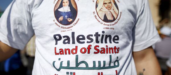 A member of the faithful wears a t-shirt with the pictures of the two Palestinian nuns being canonised before Pope Francis leads a ceremony for the canonisation of four nuns at Saint Peter's square in the Vatican City, May 17, 2015 - Sputnik International