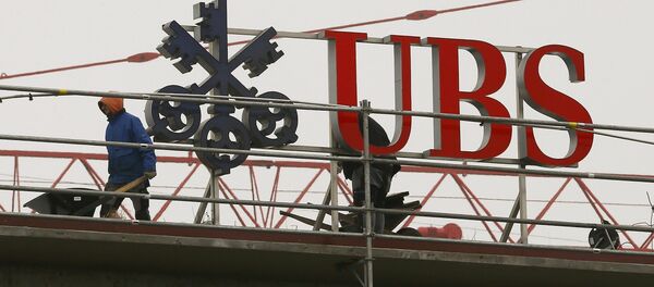 Workers are seen beside a logo of Swiss bank UBS in Zurich - Sputnik International