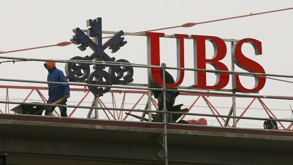Workers are seen beside a logo of Swiss bank UBS in Zurich - Sputnik International