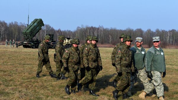 Polish soldiers watch as US troops from the 5th Battalion of the 7th Air Defense Regiment emplace a launching station of the Patriot air and missile defence system at a test range in Sochaczew, Poland - Sputnik International