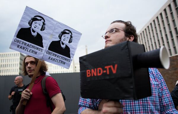 Demonstrators hold a poster showing a portrait of German Chancellor Angela Merkel reading surveillance Chancellor and a fake surveillance camera during a protest against the surveillance by the US National Security Agency, NSA. - Sputnik International