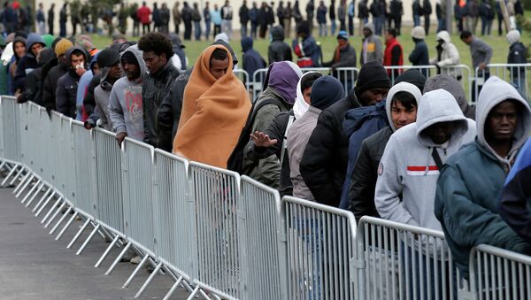 Migrants queue to receive their daily food distribution at the Jules Ferry center for migrants, in the outskirts of Calais, northern France. - Sputnik International