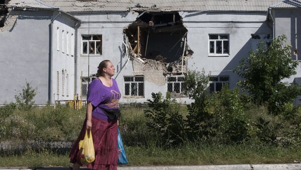 A woman walks past a damaged school in the city of Lisichansk, Luhansk region, eastern Ukraine - Sputnik International