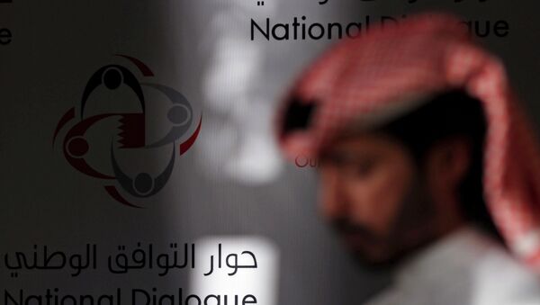 A Bahraini man walks past a display that reads, national dialogue in Arabic and English. - Sputnik International