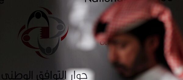 A Bahraini man walks past a display that reads, national dialogue in Arabic and English. - Sputnik International