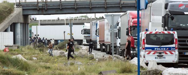 Policemen stand guard next to truck queuing to board a ferry to Great Britain to prevent migrants to reach the UK illegally, on September 10, 2014 in the French port of Calais. File Photo Policemen stand guard next to truck queuing to board a ferry to Great Britain to prevent migrants to reach the UK illegally, on September 10, 2014 in the French port of Calais. File Photo - Sputnik International