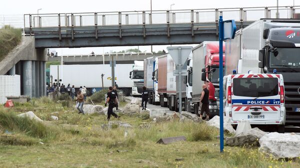 Policemen stand guard next to truck queuing to board a ferry to Great Britain to prevent migrants to reach the UK illegally, on September 10, 2014 in the French port of Calais - Sputnik International