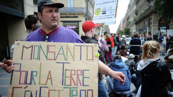 An activist holds a banner that reads 'Monsanto pour la terre c'en est trop' (Monsanto, too much for the earth) at a march against Monsanto, where 'anti-OGM31' cooperative and citizens are protesting against US agriculture and seed giant Monsanto on May 23, 2015, in Toulouse - Sputnik International