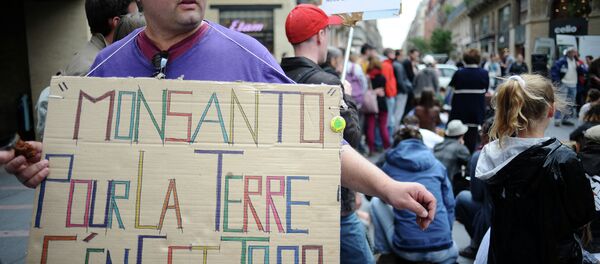 An activist holds a banner that reads 'Monsanto pour la terre c'en est trop' (Monsanto, too much for the earth) at a march against Monsanto, where 'anti-OGM31' cooperative and citizens are protesting against US agriculture and seed giant Monsanto on May 23, 2015, in Toulouse - Sputnik International
