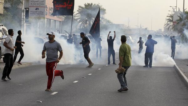 Protesters run from tear gas released by riot police to disperse them, during a march by Shi'ite Muslims in the village of Sanabis west of Manama, Bahrain, to show solidarity for victims of a suicide bomb attack in Saudi Arabia, May 23, 2015 - Sputnik International