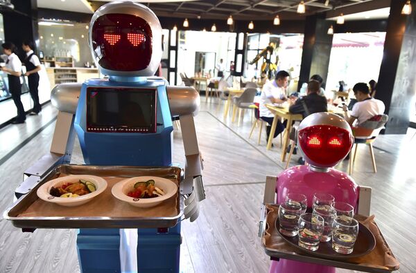 Robot couple Xiaolan (L) and Xiaotao carry trays of food at a restaurant in Jinhua, Zhejiang province, China, May 18, 2015 - Sputnik International