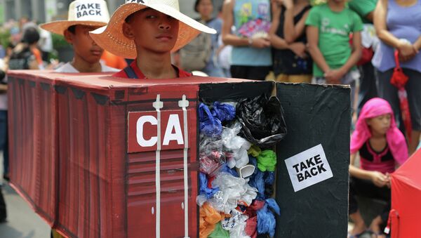 Filipino environmental activists wear a mock container vans filled with garbage to symbolize the 50 containers of waste that were shipped from Canada to the Philippines two years ago, as they hold a protest outside the Canadian embassy at the financial district of Makati, south of Manila, Philippines on Thursday, May 7, 2015 - Sputnik International