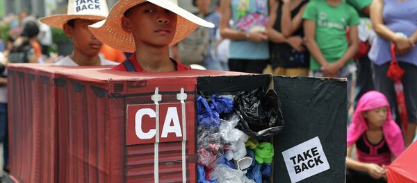 Filipino environmental activists wear a mock container vans filled with garbage to symbolize the 50 containers of waste that were shipped from Canada to the Philippines two years ago, as they hold a protest outside the Canadian embassy at the financial district of Makati, south of Manila, Philippines on Thursday, May 7, 2015 Filipino environmental activists wear a mock container vans filled with garbage to symbolize the 50 containers of waste that were shipped from Canada to the Philippines two years ago, as they hold a protest outside the Canadian embassy at the financial district of Makati, south of Manila, Philippines on Thursday, May 7, 2015 - Sputnik International