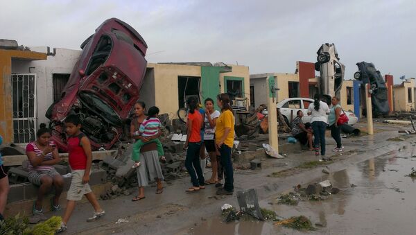 Residents stand outside their homes as damaged cars are seen after a tornado hit the town of Ciudad Acuna, state of Coahuila, May 25, 2015 - Sputnik International