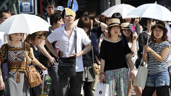 People wait for a green light at a crossing as they use umbrellas and hats to shade themselves from the sunshine in Tokyo - Sputnik International