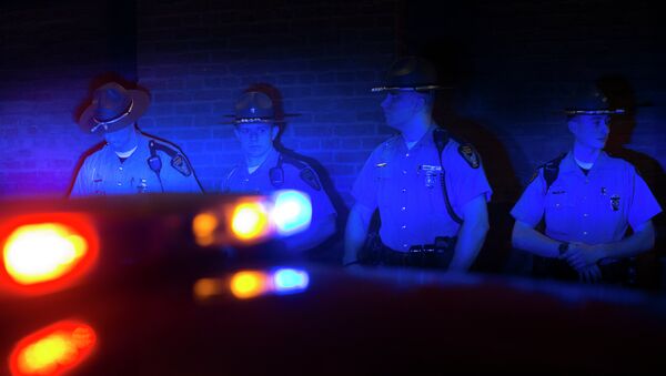 Police officers are illuminated by patrol car lights during a protest against the acquittal of Michael Brelo, a patrolman charged in the shooting deaths of two unarmed suspects. - Sputnik International