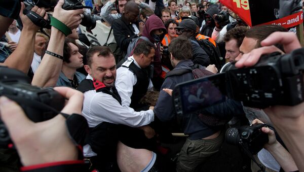 A demonstrator is held by two police officers surrounded by other protesters and members of the media during an anti-austerity, anti-Conservative Party protest after the Queen's Speech was delivered to Parliament in London, Wednesday, May 27, 2015. - Sputnik International