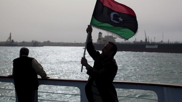 A man holds a pre Moammar Gadhafi flag. - Sputnik International