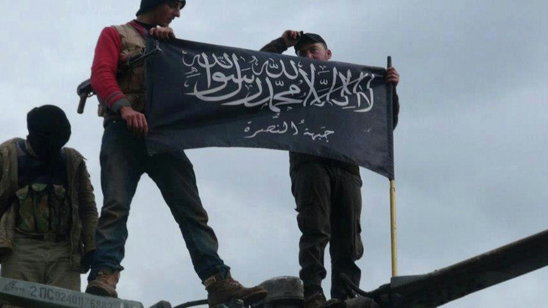 Rebels from al-Qaida-affiliated Jabhat al-Nusra, also known as the Nusra Front, wave their brigade flag, as they step on the top of a Syrian air force helicopter. - Sputnik International, 1920, 02.10.2021