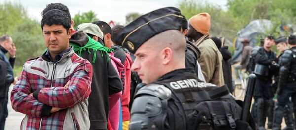Police watch migrants gathered outside the Jules Ferry day care center for migrant - Sputnik International