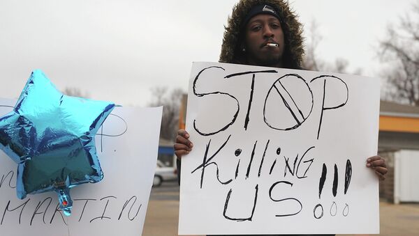 A demonstrator holds up a poster standing next to a makeshift memorial for a black teen shot dead by a white officer at the Mobil On-The-Run gas and convenience store in Berkeley, Missouri - Sputnik International