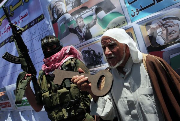 Palestinian militants of the Ezzedine al-Qassam Brigades, Hamas' armed wing, stand with an old Palestinian man holding a wooden key during a parade in the southern Gaza Strip town of Rafah on May 17, 2015 to mark the 67th anniversary of the Nakba - Sputnik International