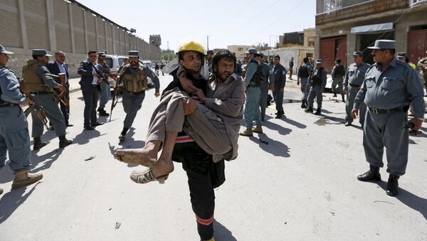 An Afghan policeman carries an injured man after an attack in Kabul, Afghanistan in this May 17, 2015 file photo - Sputnik International