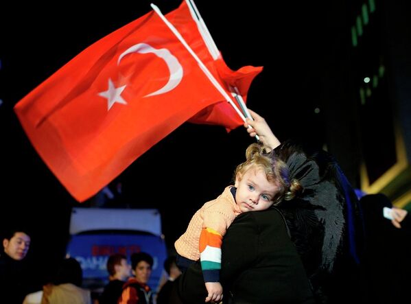 A supporters of Turkey's ruling Justice and Development Party holds a baby as she waves Turkish flags in Istanbul,Turkey, late Sunday, June 7, 2015. - Sputnik International
