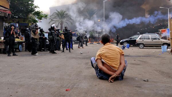 A handcuffed protester sits on the ground as Egyptian security forces move in to disperse supporters of Egypt's ousted president Mohamed Morsi by force in a huge camp in Cairo's Al-Nahda square on August 14, 2013 - Sputnik International