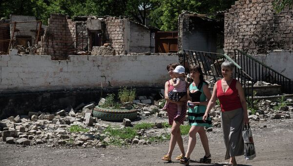 Residents walk in front of destroyed building as a result of shelling on June 8, 2015 in Novotoshkivske village, Donetsk region - Sputnik International