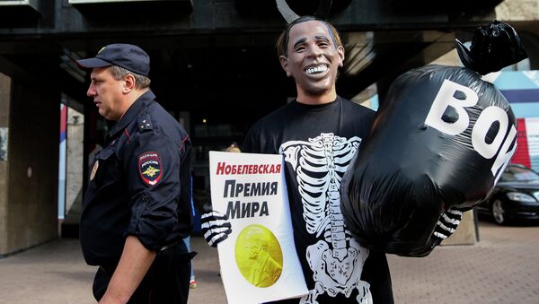 Russian Communist Party activist, wearing a mask depicting US President Barack Obama, holds a poster reading Nobel Peace Prize in one hand and a bag reading War in the other, takes part at a picket outside the UN mission in Moscow, Russia, Tuesday, Sept. 9, 2014 - Sputnik International