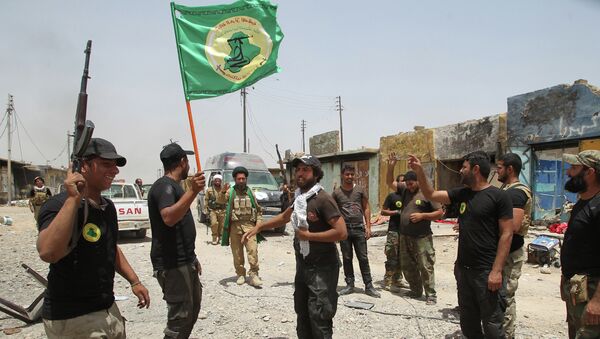 Iraqi Shiite fighters from the Popular Mobilisation force raise their flag in the city of Baiji, north of Tikrit, as they advance against the Islamic State jihadist group to try to retake the strategic town for a second time, on June 8, 2015 - Sputnik International