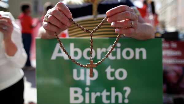 A file photo taken on July 10, 2013 shows a protester holding rosary beads and holding an anti-abortion placard in front of the gates of the Irish Parliament building in Dublin during a demonstration ahead of a vote to introduce abortion in limited cases where the mother's life is at risk - Sputnik International