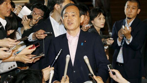 Japan's Chief Cabinet Secretary Yoshihide Suga (C) is surrounded by reporters as he holds an emergency news conference following the eruption of a volcano in southern Japan, at prime minister Shinzo Abe's official residence in Tokyo, in this photo taken by Kyodo May 29, 2015 - Sputnik International