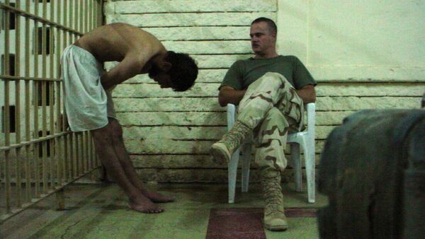 This is an image obtained by The Associated Press which shows a detainee bent over with his hands on the bars of a prison cell watched by a soldier in late 2003 at the Abu Ghraib prison in Baghdad, Iraq - Sputnik International