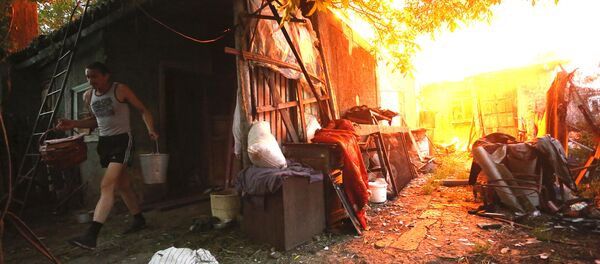 A resident carries out his belongings to save them from the fire after shelling on the outskirts of Donetsk on June 9, 2015. A resident carries out his belongings to save them from the fire after shelling on the outskirts of Donetsk on June 9, 2015. - Sputnik International