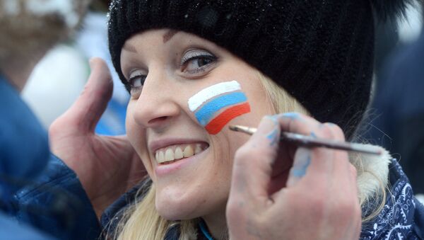 A young man paints a small Russian flag on the cheek of a Russian girl. - Sputnik International