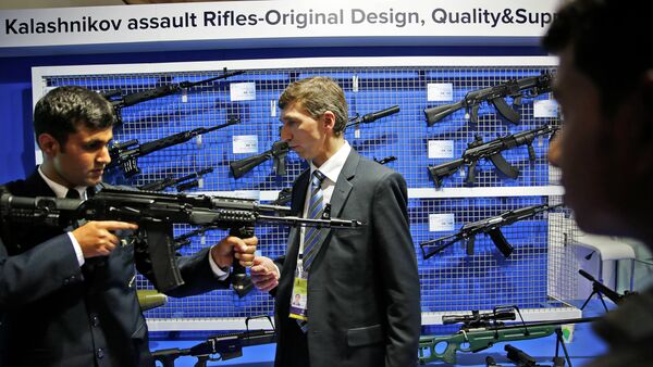 A Russian exhibitor from Kalashnikov, center, explains the working of an AK-104 at the 8th International Land and Naval Defense system exhibition, in New Delhi, India, Thursday, Feb. 6, 2014 - Sputnik International