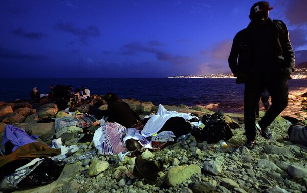 Migrants sleep on the rocks by the sea in Ventimiglia, at the border between Italy and France, early Monday, June 15, 2015 - Sputnik International