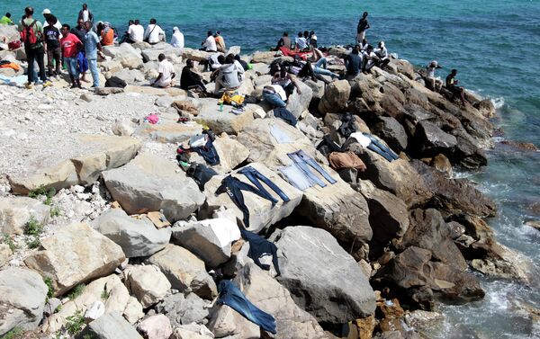 Migrants dry their clothes on rocks as they wait to cross into France, in the Italian city of Ventimiglia, on the French-Italian border, on June 14, 2015 - Sputnik International