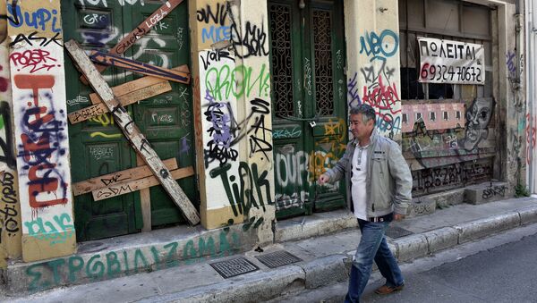 A man walks past abandoned buildings with 'for sale' sign in central Athens, on May 13, 2015. - Sputnik International