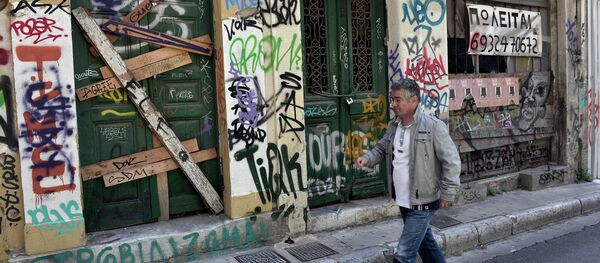 A man walks past abandoned buildings with 'for sale' sign in central Athens, on May 13, 2015. - Sputnik International