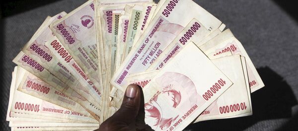 A man poses with a handful of Zimbabwean dollars at a bank in central Harare, June 15, 2015 - Sputnik International